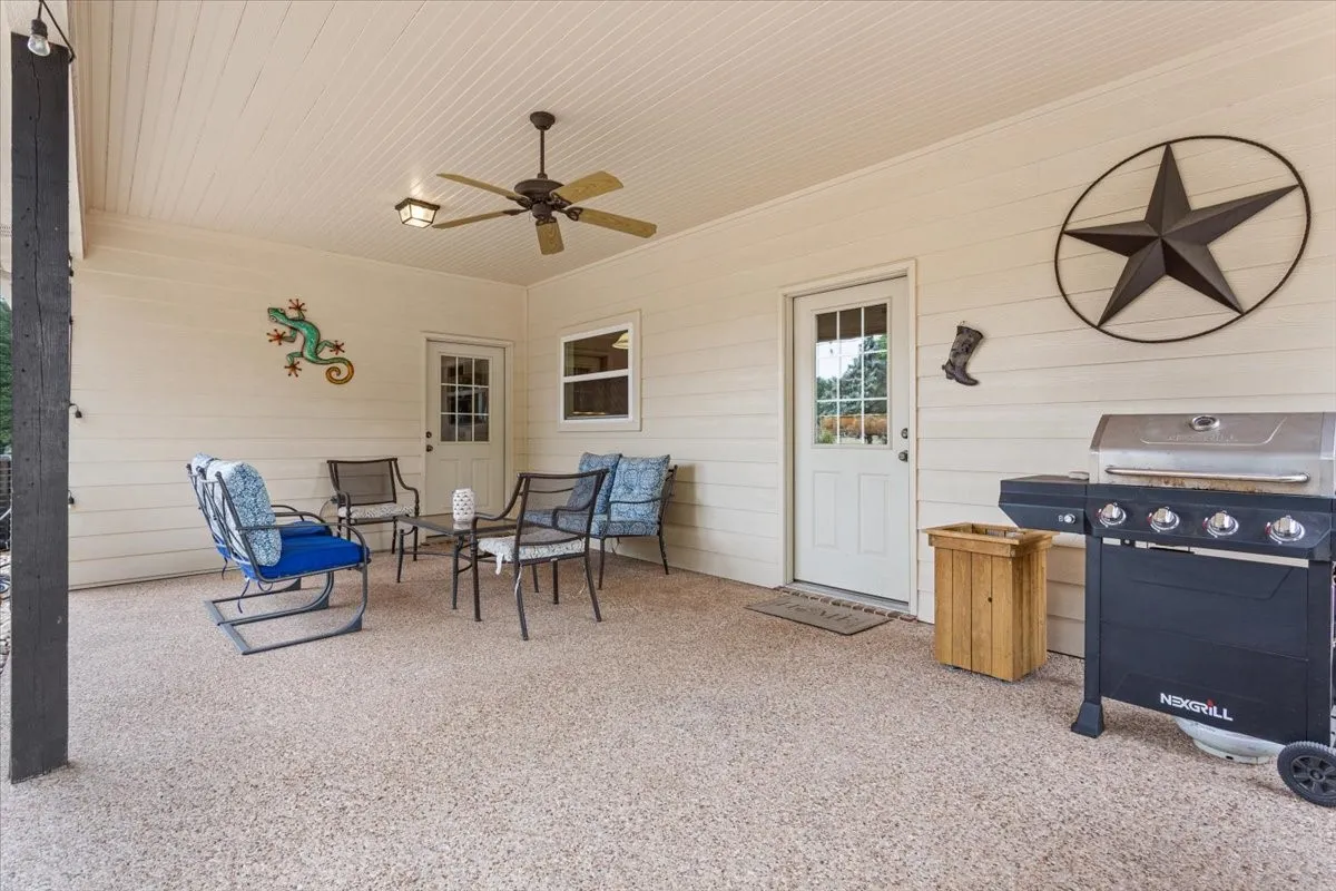 Covered patio featuring an exposed aggregate concrete floor, beadboard ceiling, and ceiling fan with integrated lighting