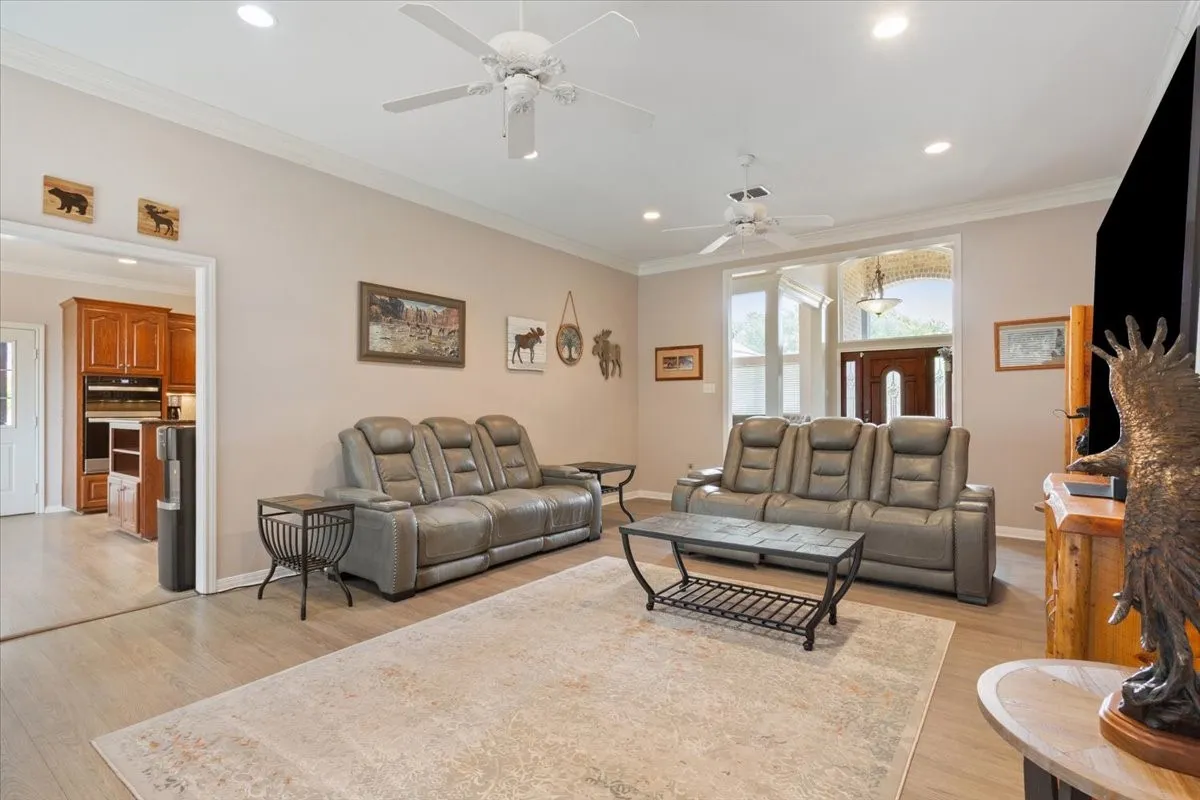 Recessed lighting, crown molding, wood-finish flooring, two ceiling fans, and a paneled entry door with sidelights