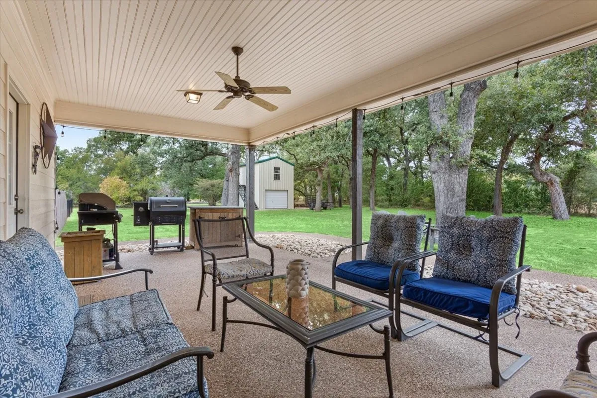 Covered patio with beadboard ceiling, ceiling fan, string lighting, and an aggregate concrete surface