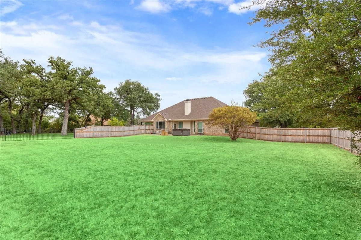 Expansive green lawn with mature trees and a wooden privacy fence