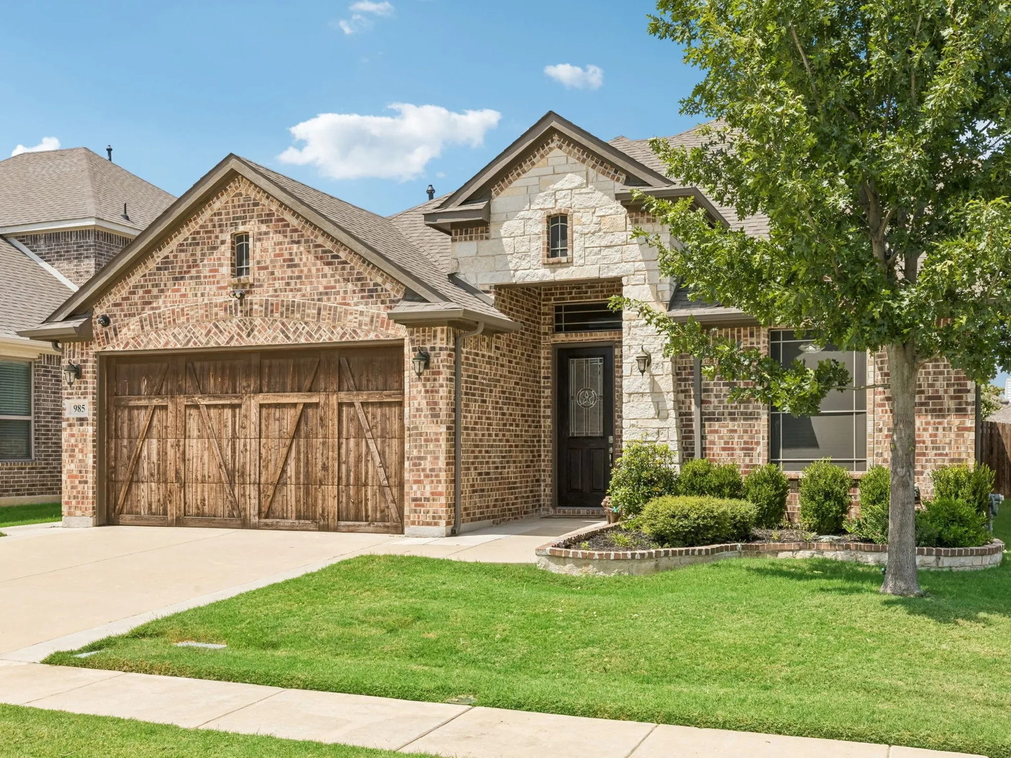 Brick and stone facade with a decorative wood-finish garage door