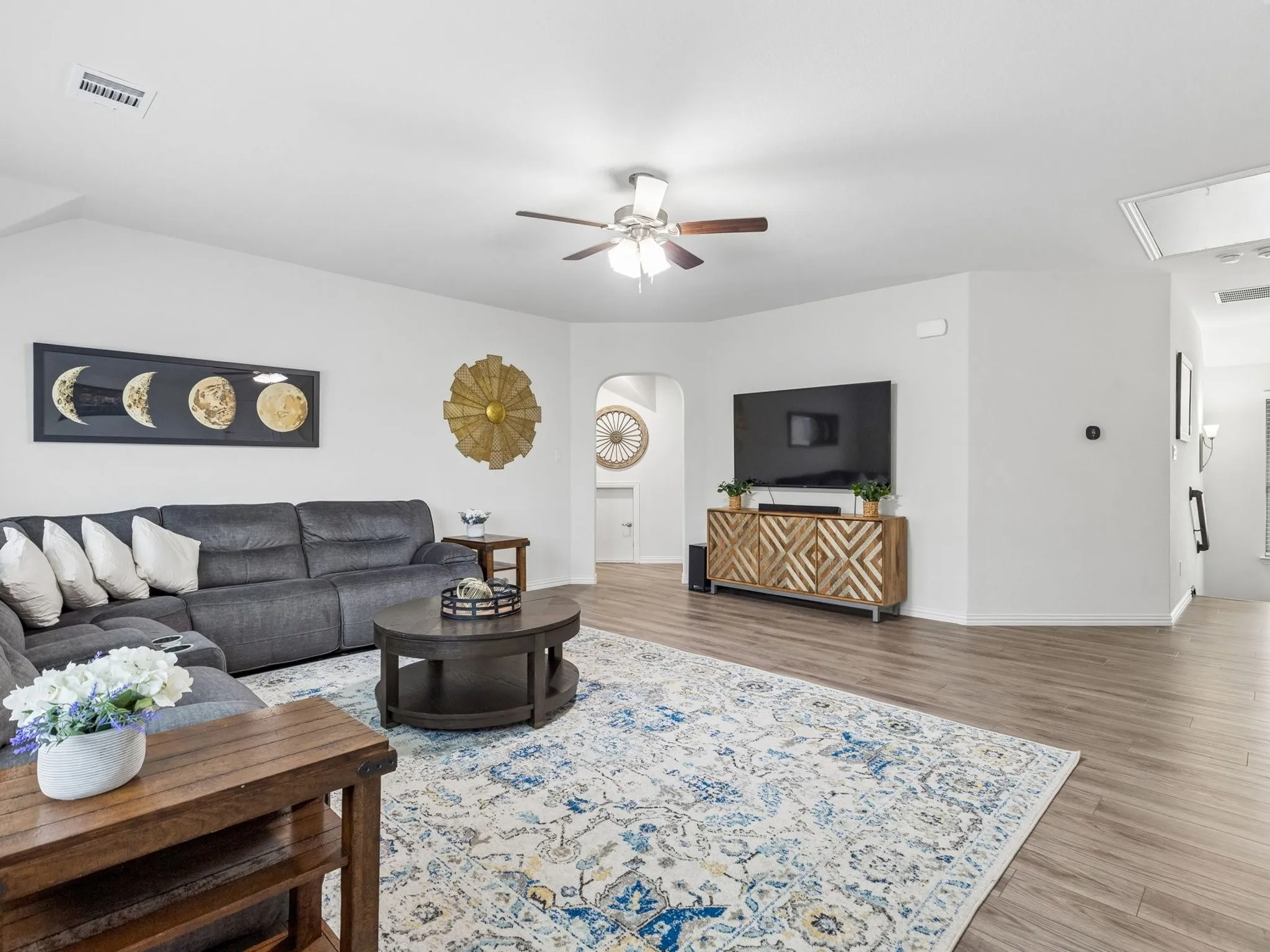 Spacious living area featuring LVP wood-finish flooring, a ceiling fan, and an arched doorway