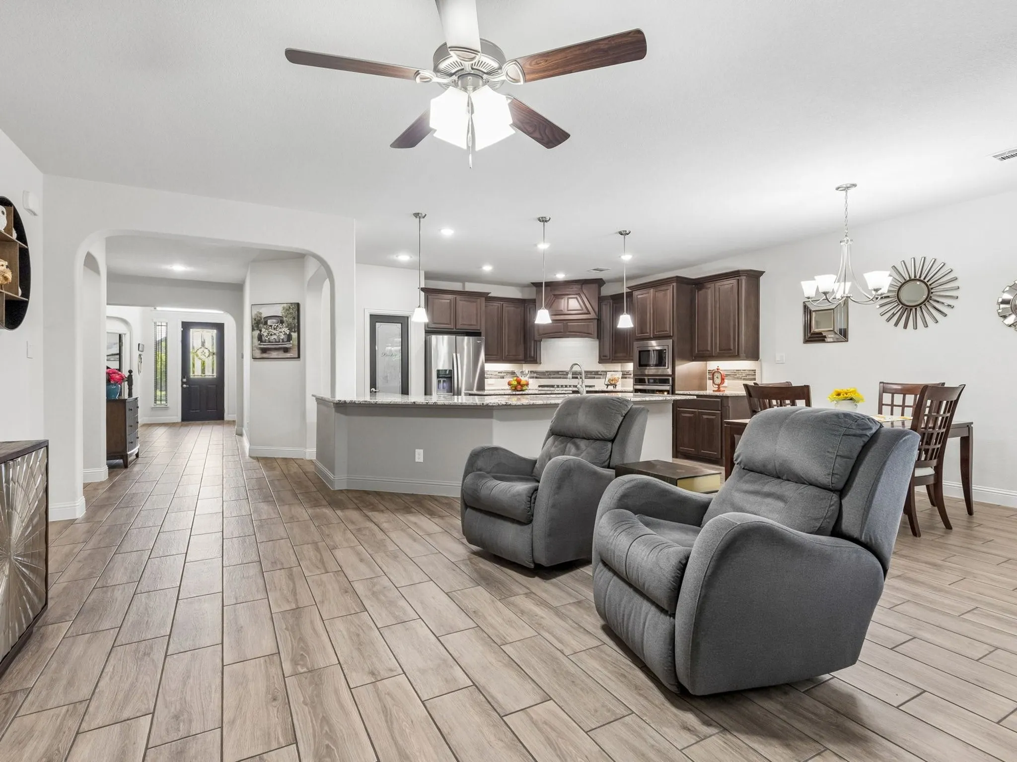 Wood-finish tile flooring throughout, dark wood-finish cabinetry, stainless steel appliances, recessed lighting, and a ceiling fan