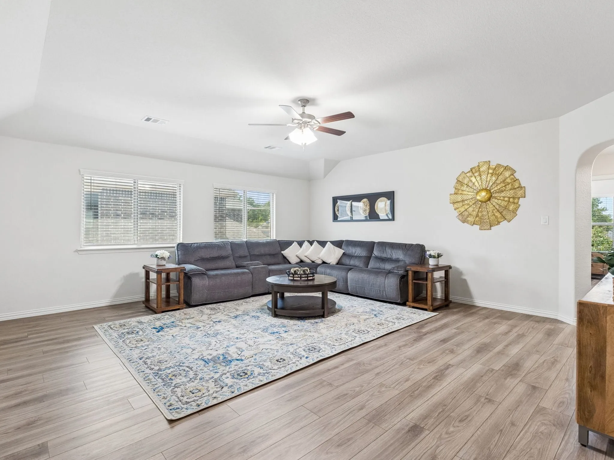 Spacious living area featuring light LVP wood-finish flooring, and a ceiling fan