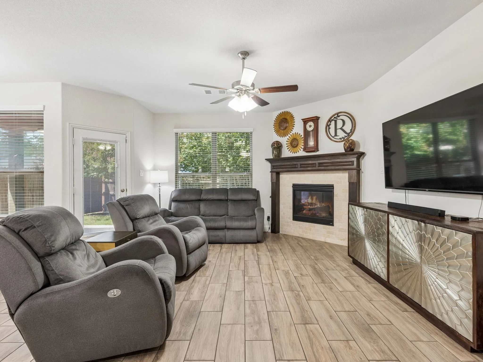 Corner gas log fireplace with a wood mantel, wood-finish tile flooring, and multiple windows