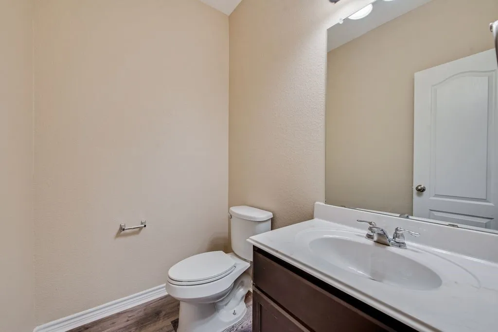 Bathroom featuring a dark wood-finish vanity with an integrated white sink, chrome faucet, and a large wall mirror