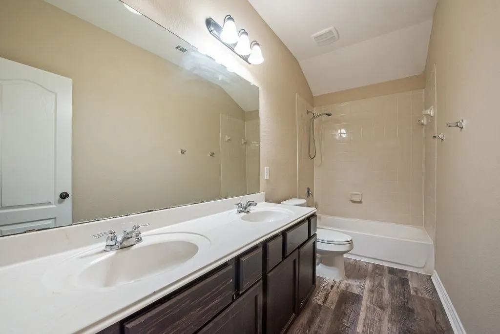 Bathroom featuring a dual vanity with integrated sinks, chrome fixtures, and dark wood-finish cabinetry