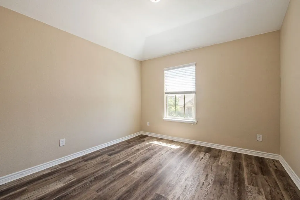 Room featuring wood-finish flooring, a single window with blinds, and light neutral wall tones