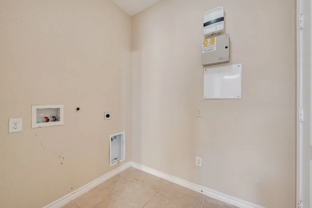 Utility area featuring a washer hookup, dryer hookup, wall outlets, and light-toned tile flooring