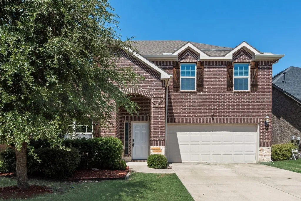 Brick exterior featuring an arched entryway, white front door, and an attached two-car garage