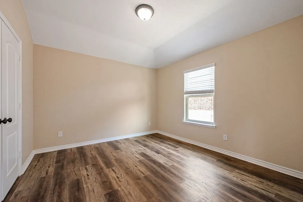 Spacious room featuring wood-finish flooring, neutral-toned walls, and a recessed ceiling