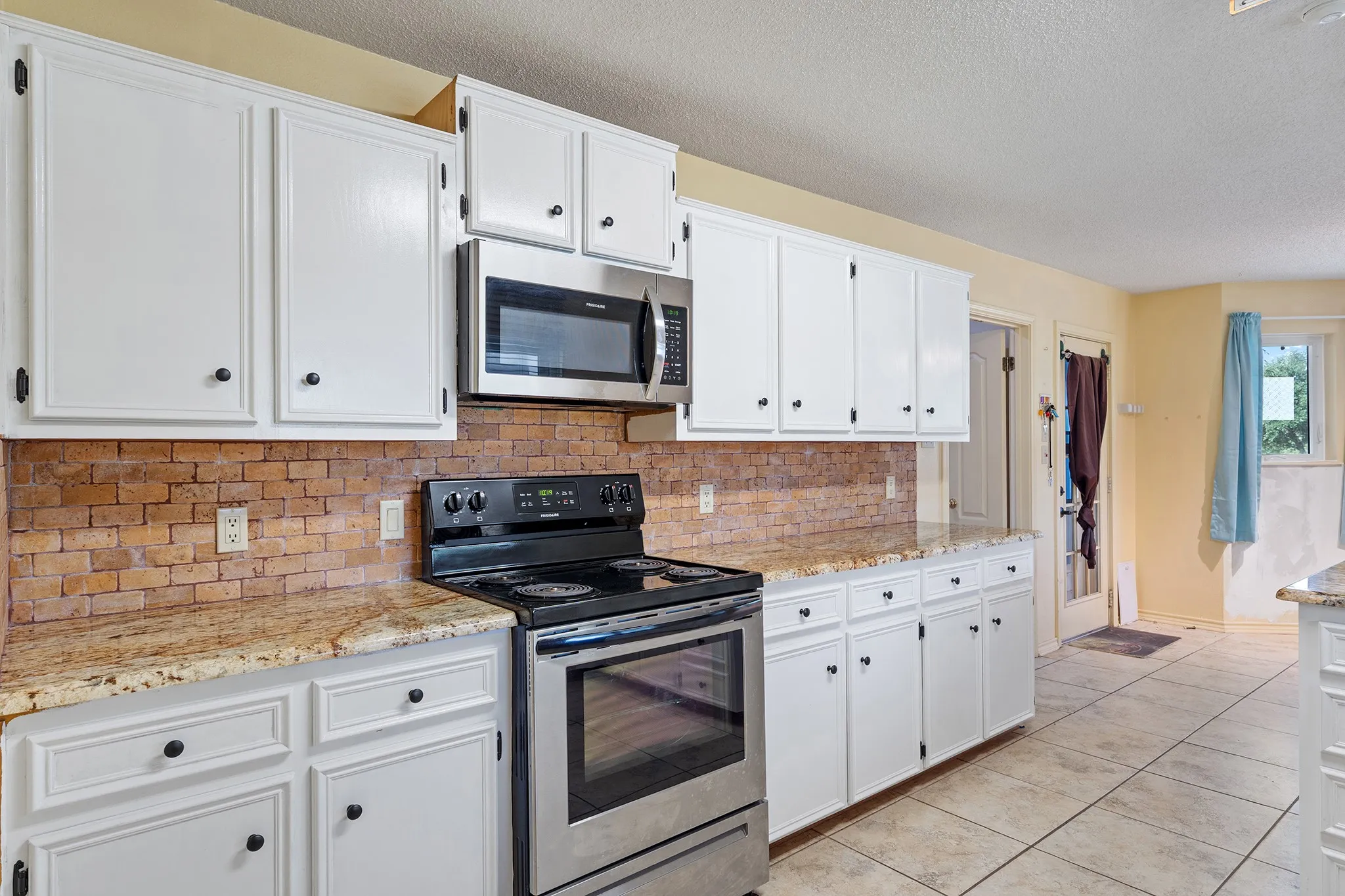 Lovely kitchen with natural style backsplash and granite counters.