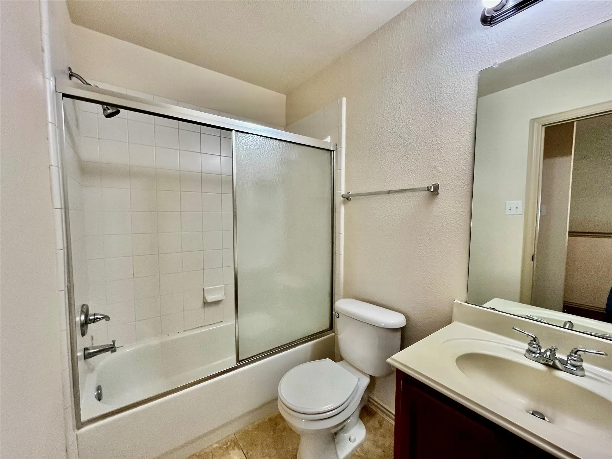 Bathroom with tub/shower, vanity, toilet, and tile flooring