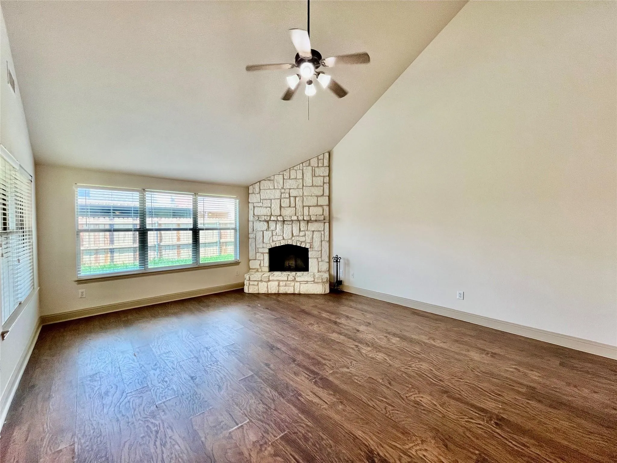 Living room with wood flooring, ceiling fan, and windows