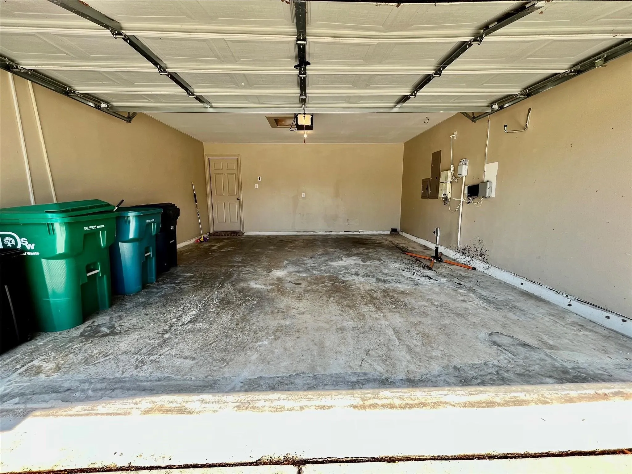 Spacious garage with concrete flooring and storage items.