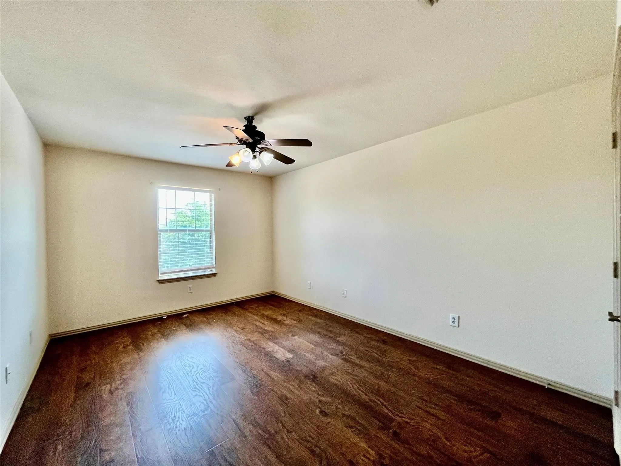 Bedroom with wood flooring, ceiling fan, window, and closet.
