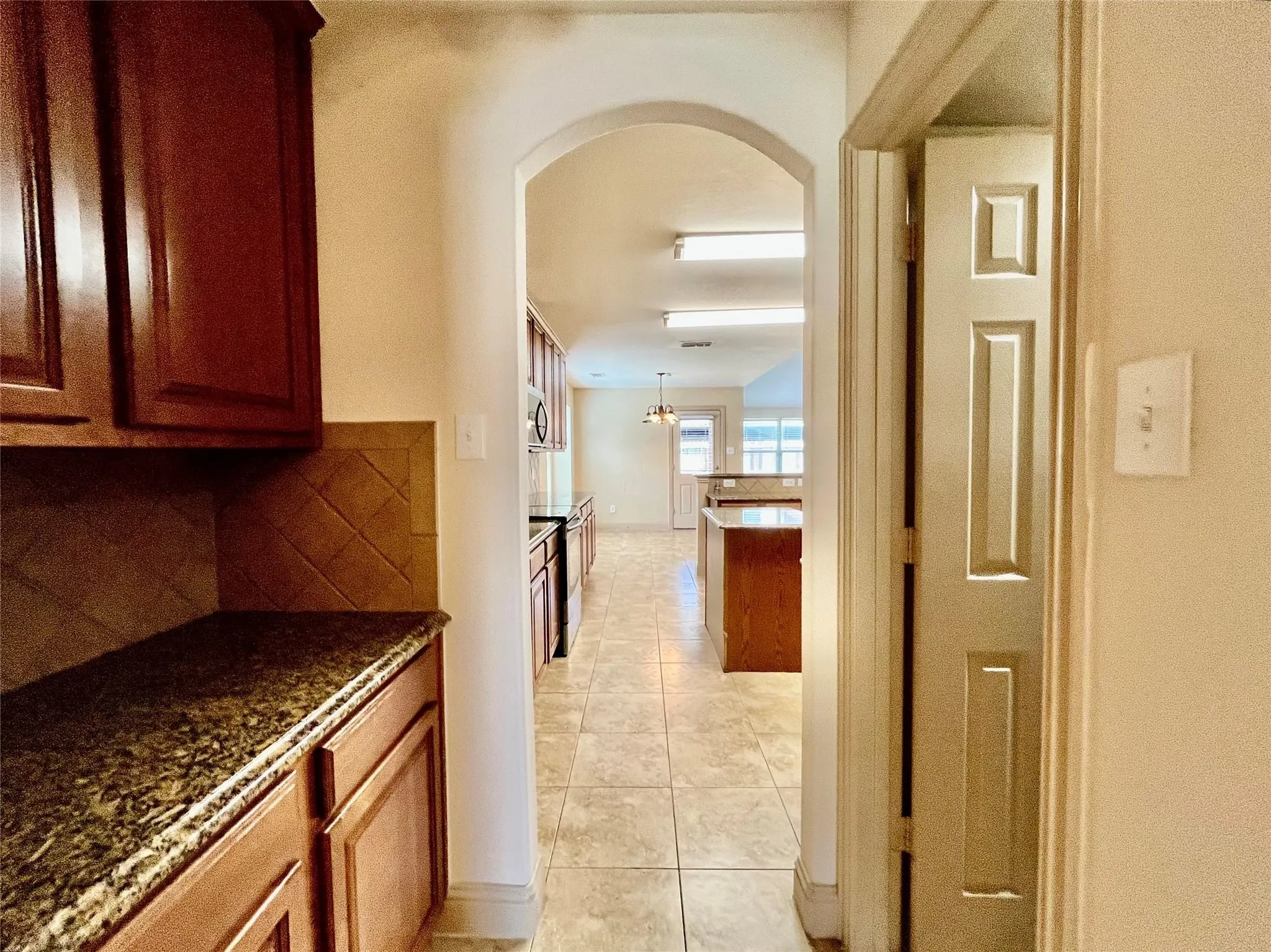 Hallway with wood flooring, doorway, and access to kitchen