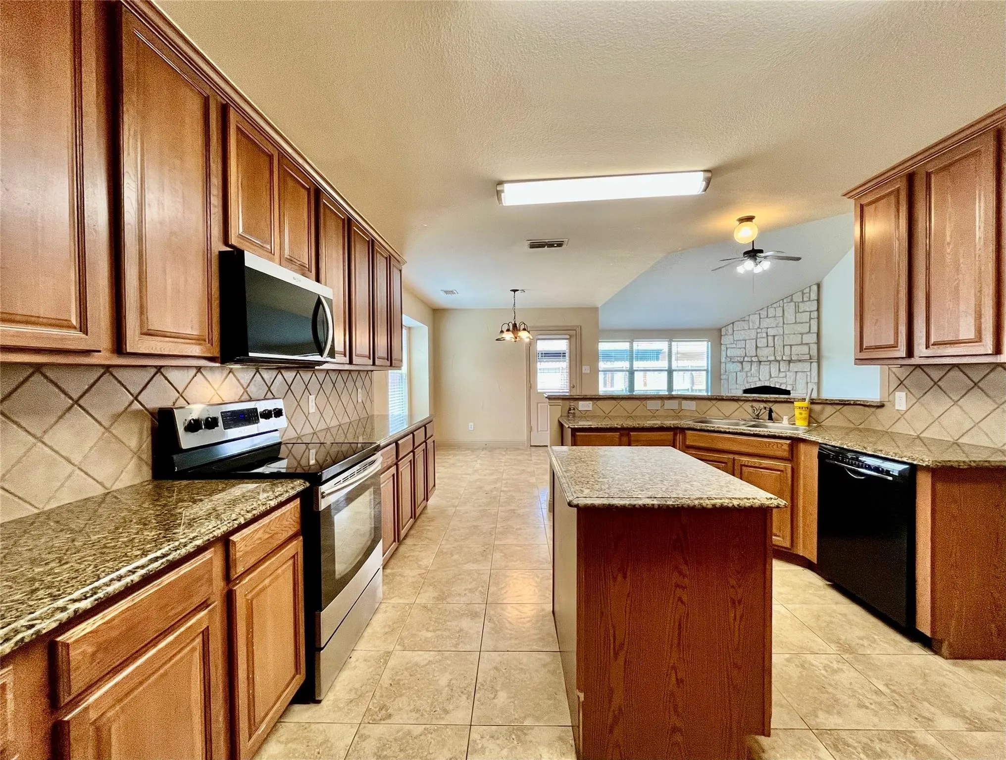 Kitchen with wood cabinets, island, countertops, and appliances