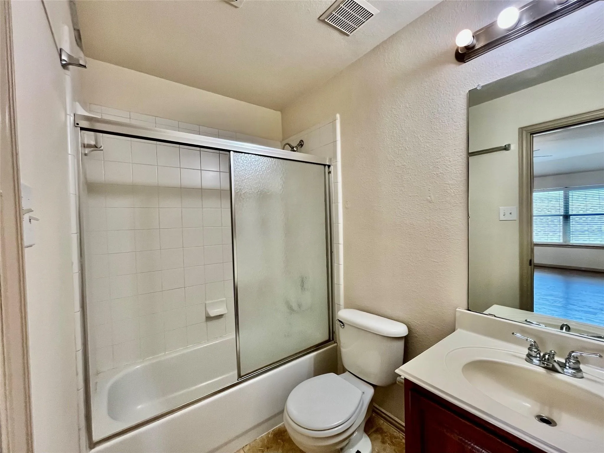Bathroom with tub/shower, vanity, toilet, and tile flooring