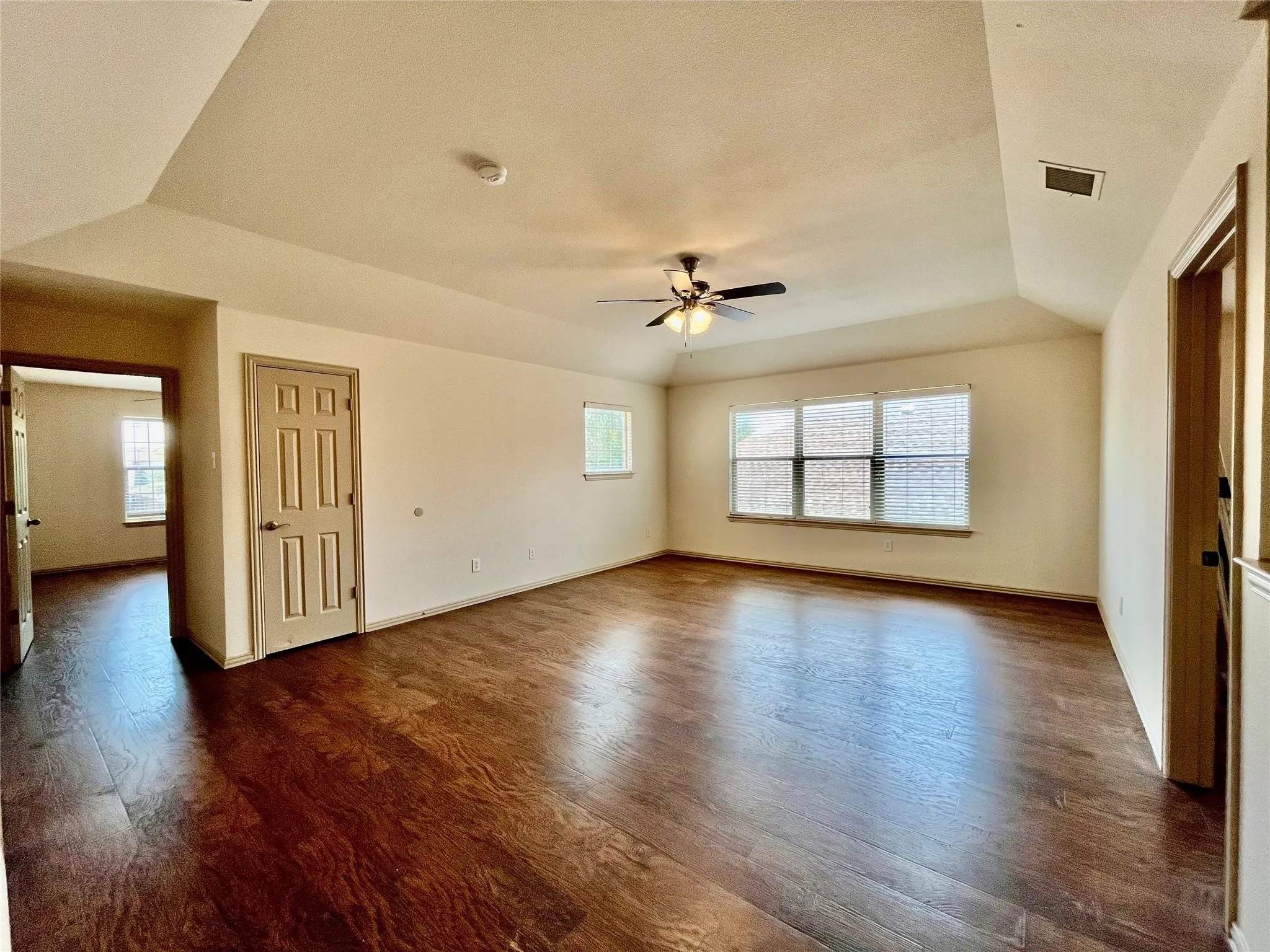 Spacious living room with wood flooring, ceiling fan, and windows