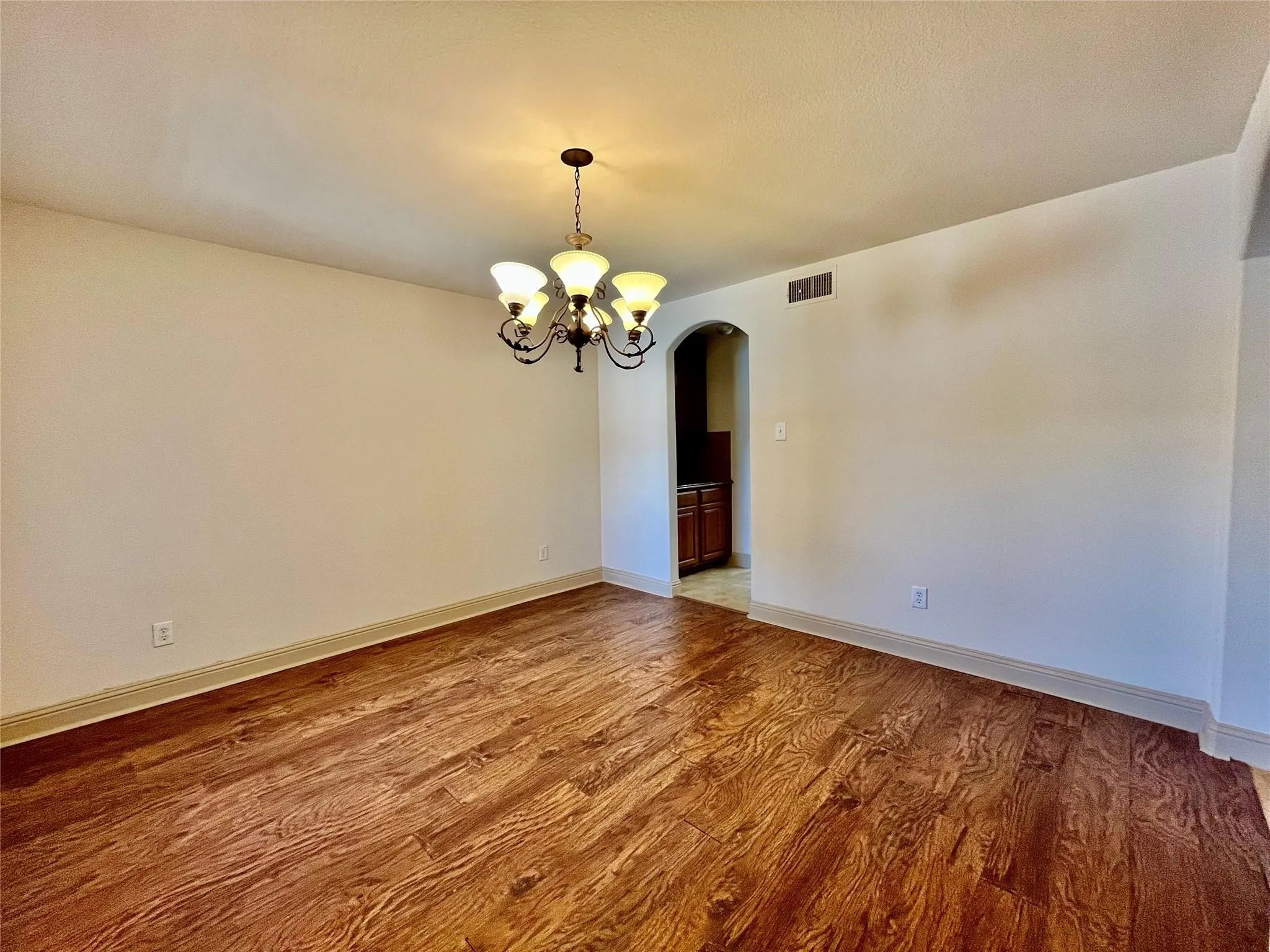 Open living area with wood flooring, ceiling fan, and hallway access