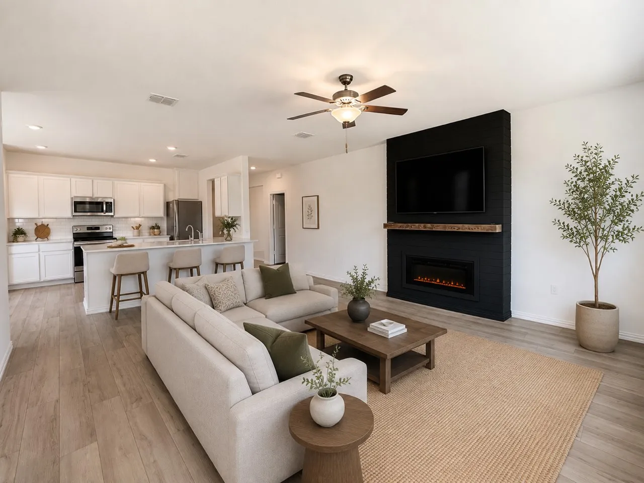Open-concept living area featuring wood-finish flooring, a contemporary fireplace with a wood mantle, and a ceiling fan with integrated lighting