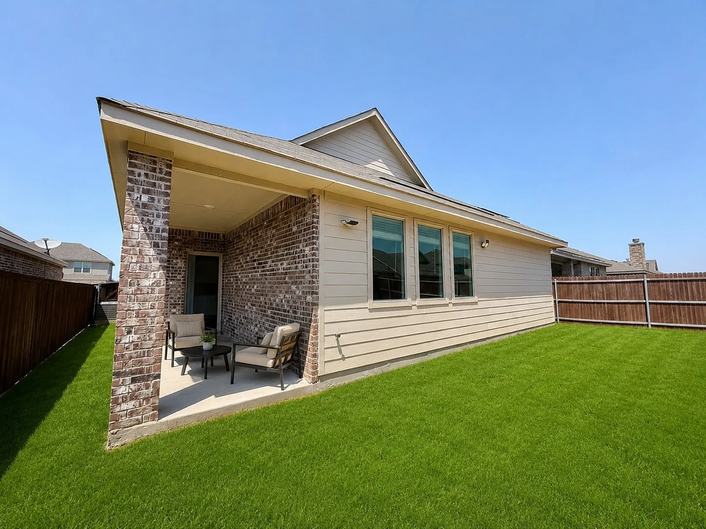 Covered patio with brick columns, siding exterior, and a manicured lawn