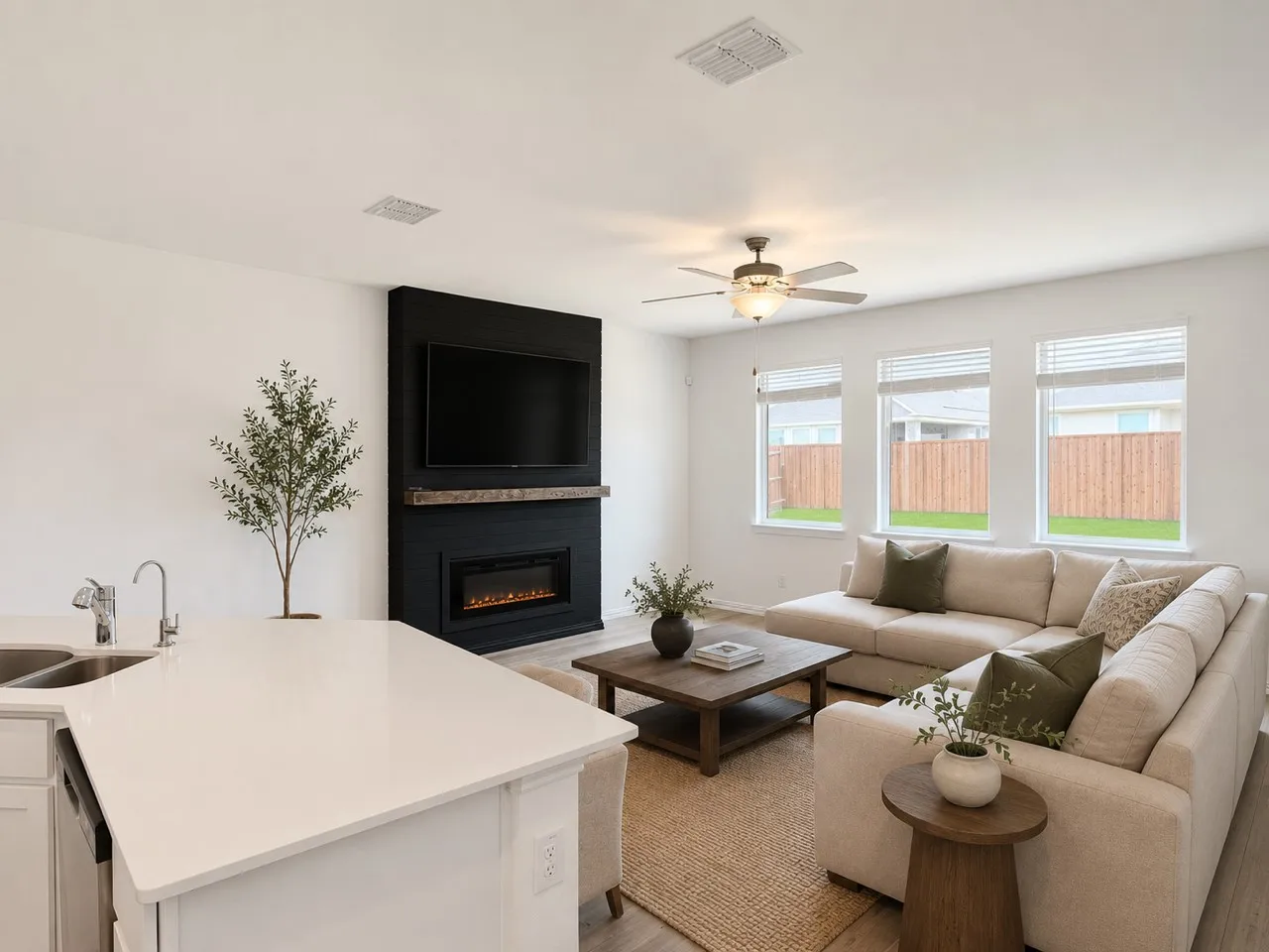 Open-concept living space featuring wood-finish flooring, a contemporary fireplace with a wood mantle, a ceiling fan, and multiple windows