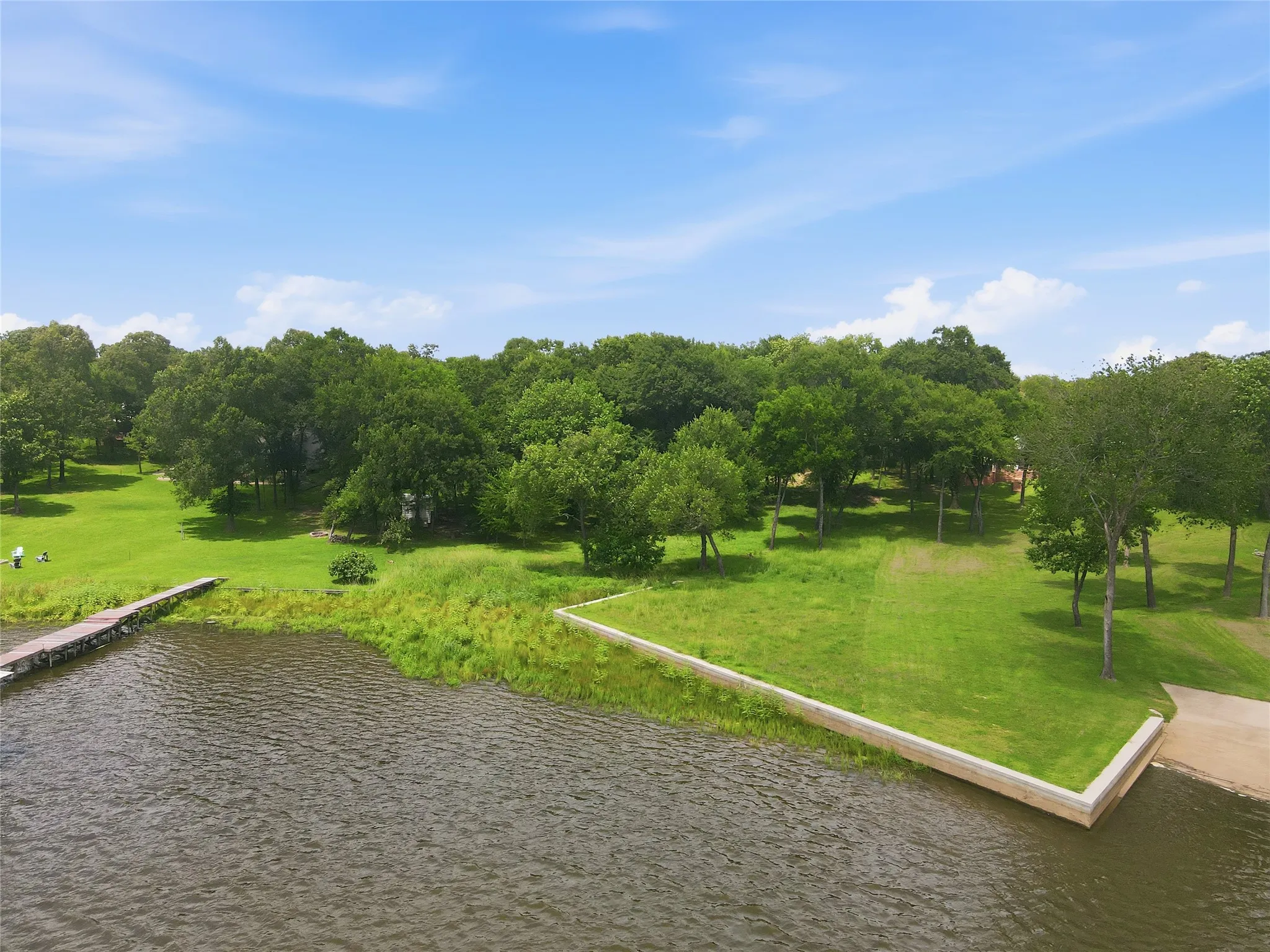 Expansive grassy areas, mature trees, and direct water access with a dock and boat ramp