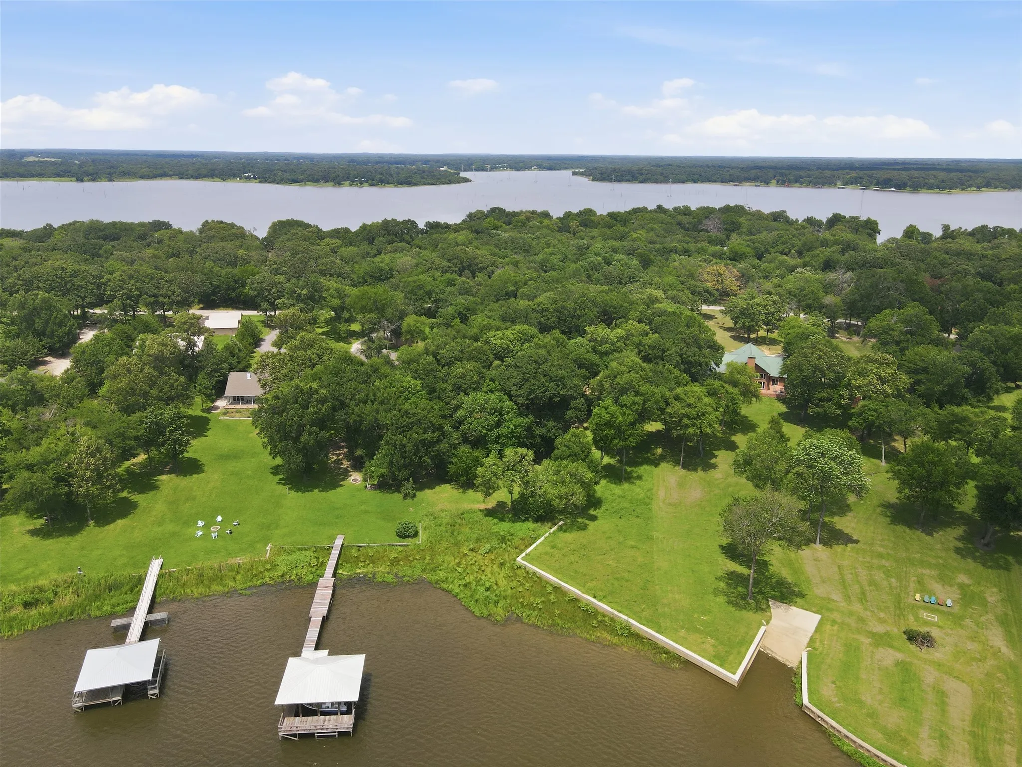 Expansive waterfront property with two boat docks, a boat ramp, and lush, treed surroundings