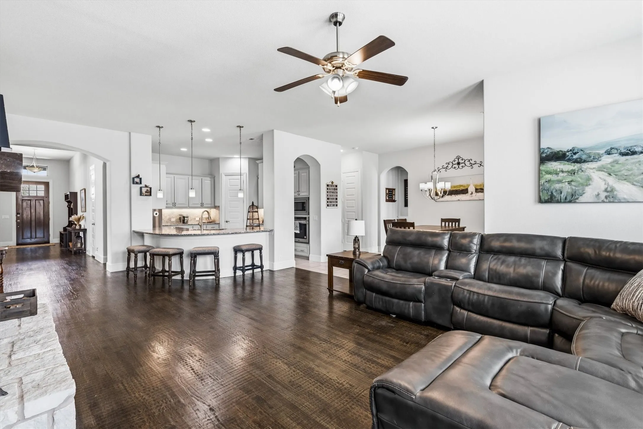 The spacious family room connects seamlessly to the kitchen through arched openings, with tall ceilings adding to the airy feel. Rich hardwood floors and a stone gas fireplace bringing warmth to the room. The kitchen bar seating keeps everyone close while your're cooking or entertaining.