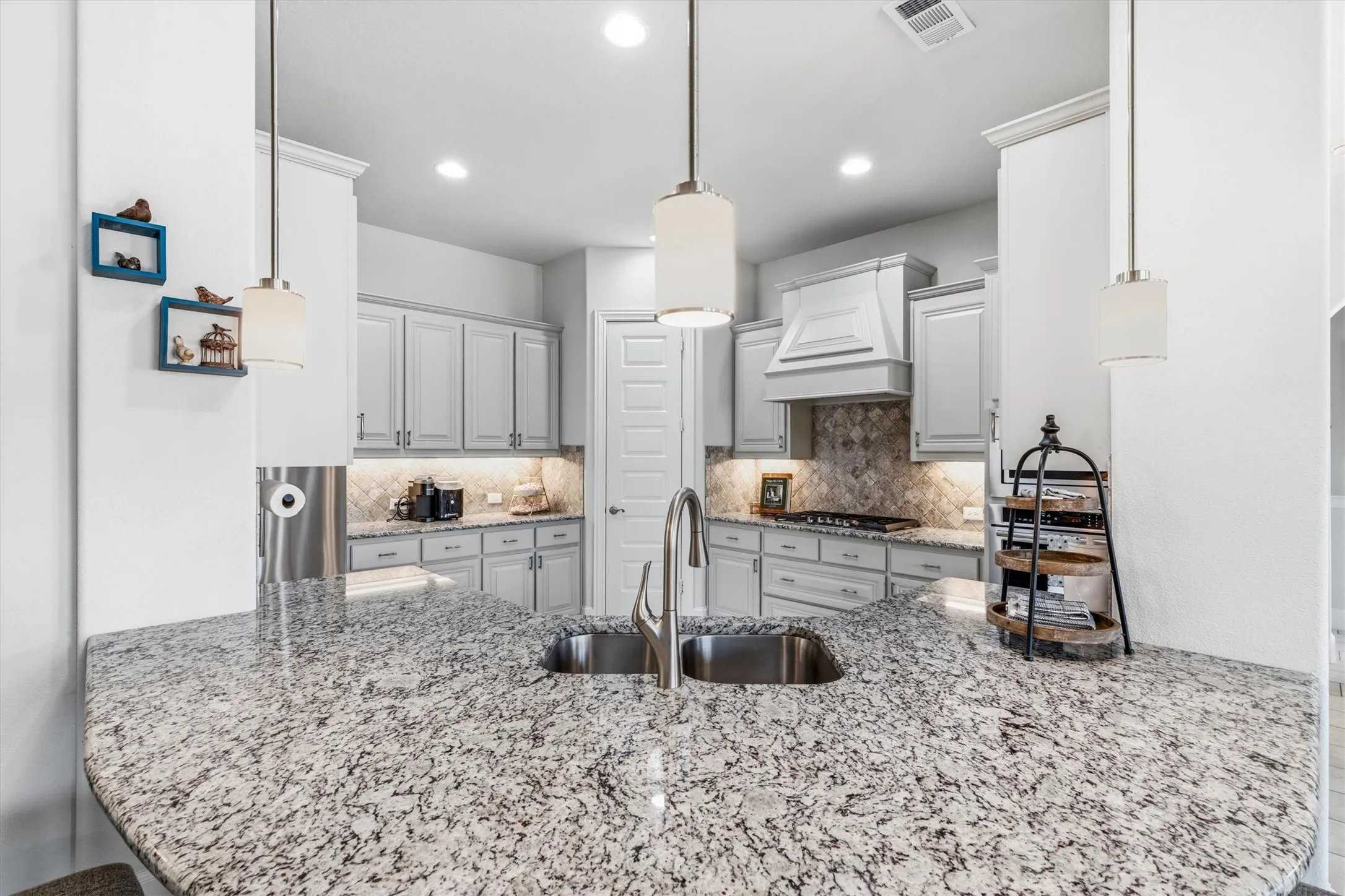 Bright spacious kitchen with granite countertops and a large island offer plenty of room for homework, meal prep or gatherings. Designer vent hood anchors the gas cooktop. Recess and pendant lighting.