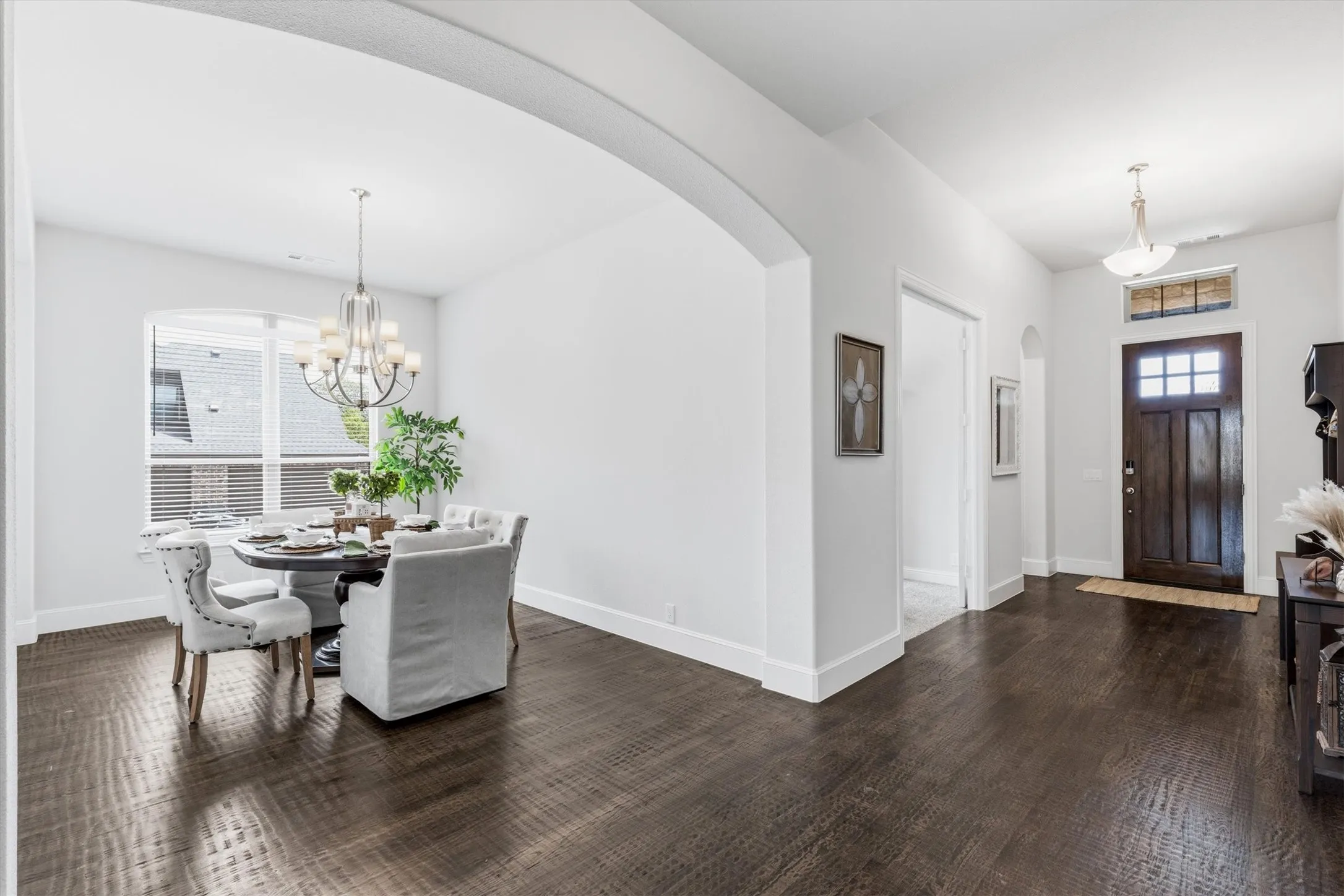 A wide, open entryway welcomes you in, guiding you past a front bedroom and bathroom, an office with french glass doors and to an archway showcasing the dining space.