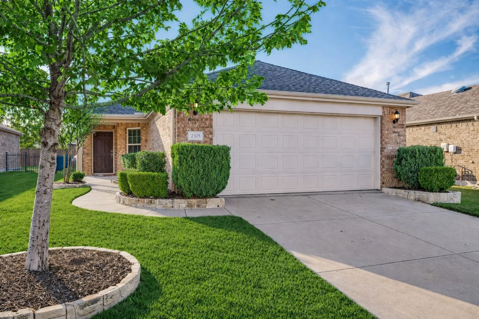 Brick exterior with an attached garage, concrete driveway, and a concrete walkway