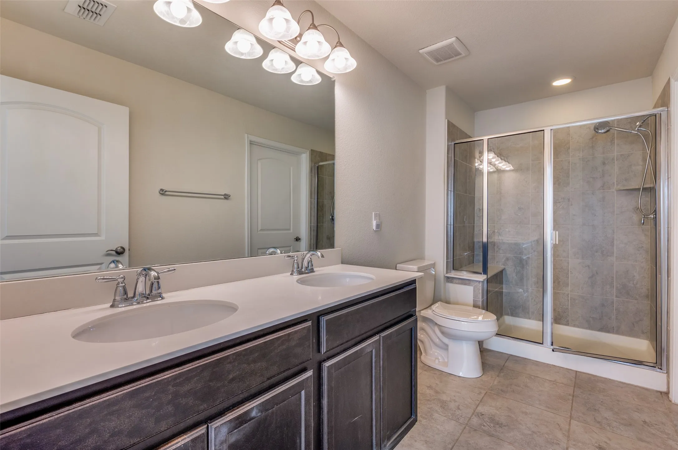 Dual vanity with integrated sinks, expansive wall mirror, and overhead lighting