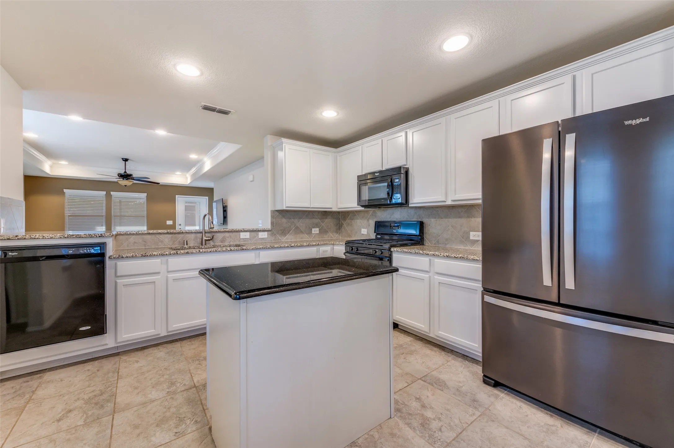 Kitchen featuring white cabinetry, a central island with a dark countertop, tile flooring, and stainless steel appliances