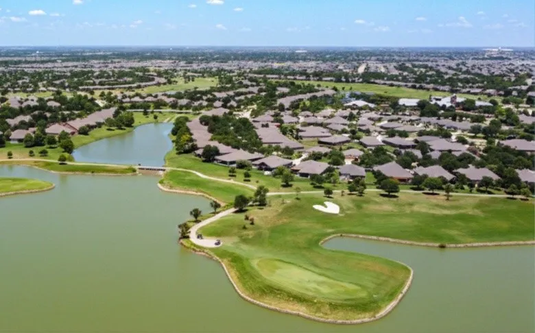 Expansive residential area featuring numerous homes with brown roofs, surrounding a large body of water