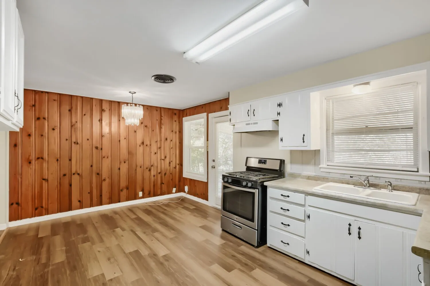 Spacious kitchen featuring white cabinetry, stainless steel appliances, laminate countertops, and a single-basin sink with chrome fixtures