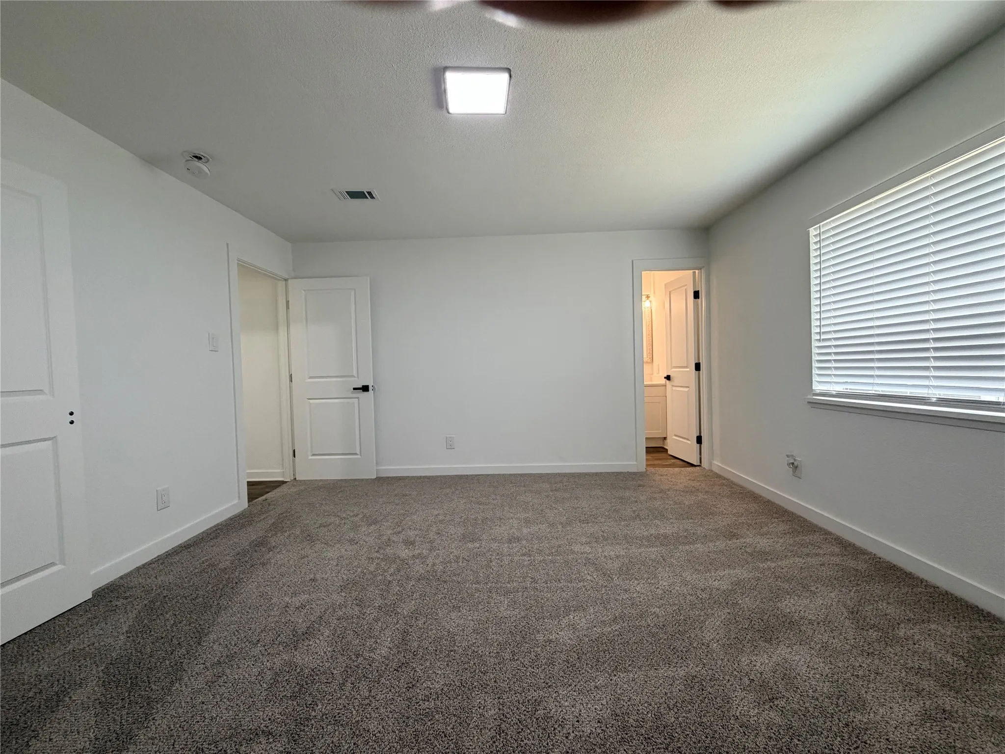 Plush gray carpeting, white walls, and a square ceiling light fixture