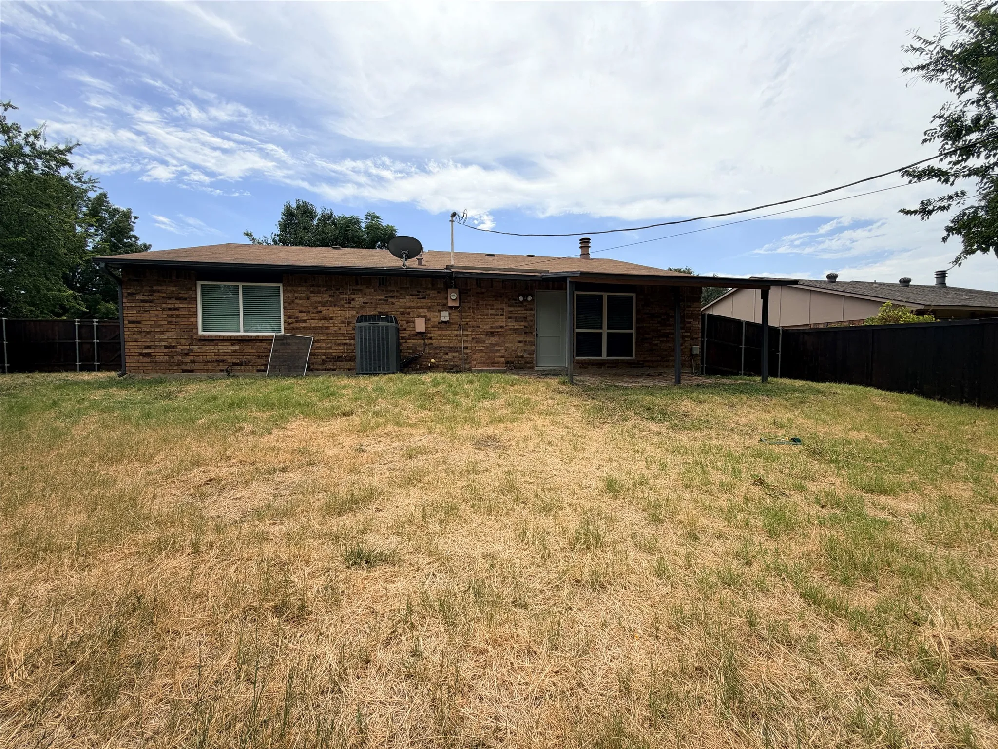 Brick exterior with a covered patio and a partially fenced yard