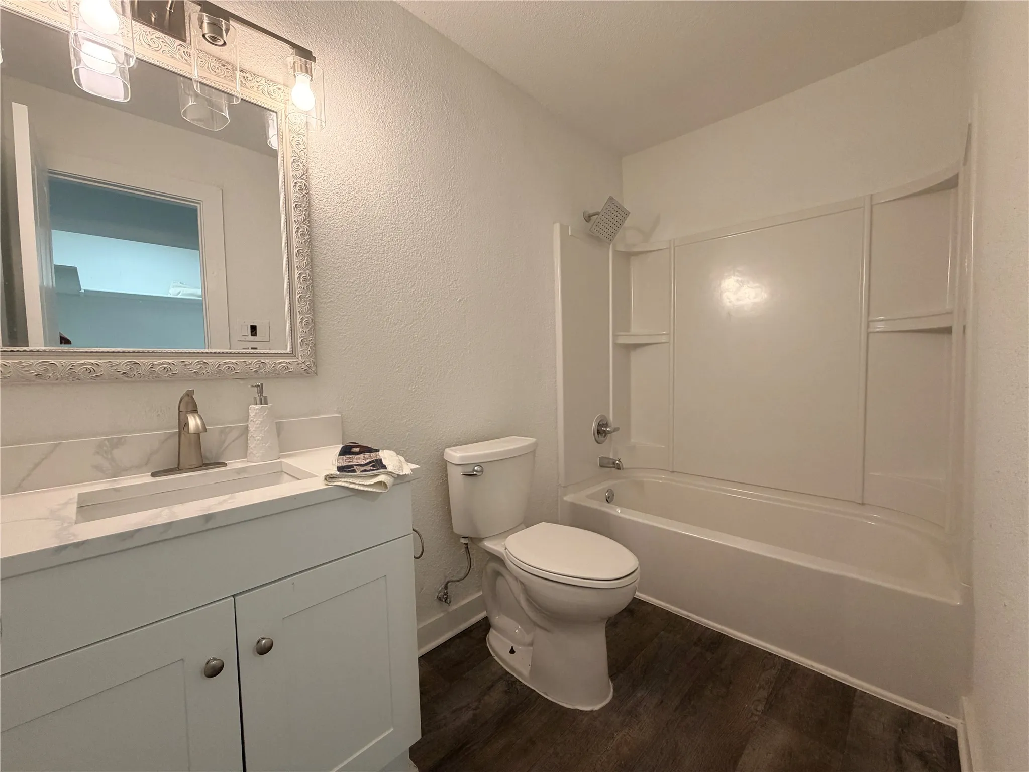 White vanity with a rectangular integrated sink, brushed nickel faucet, and decorative mirror