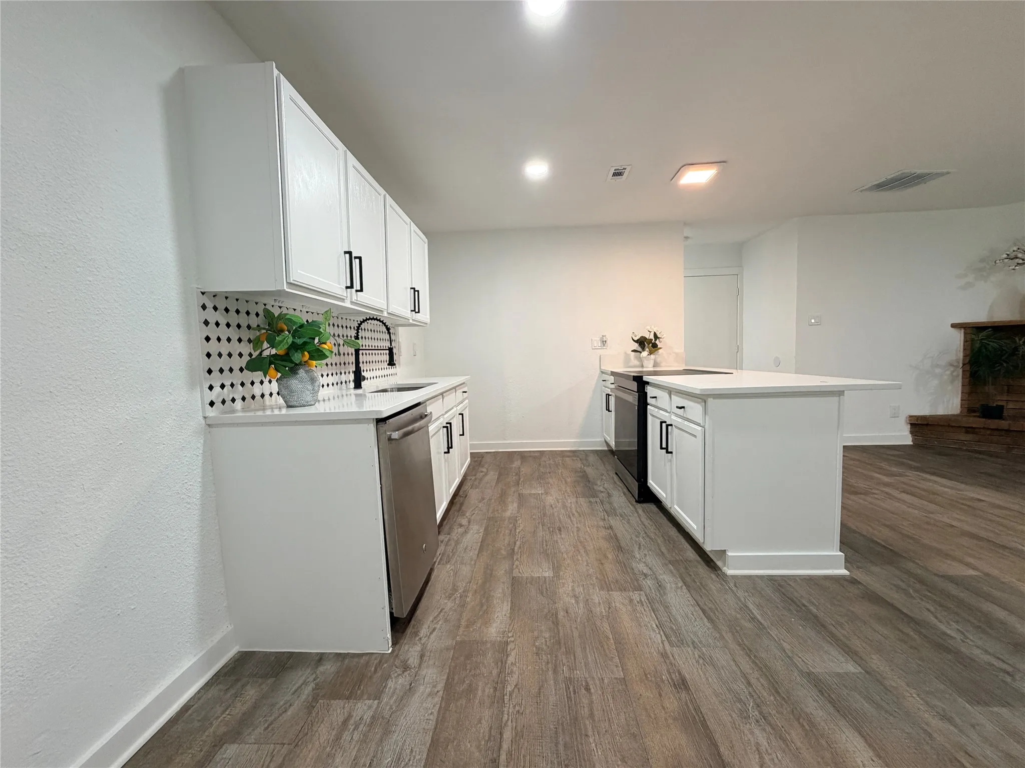 White cabinetry, dark hardware, stainless steel appliances, wood-finish flooring, and a kitchen island