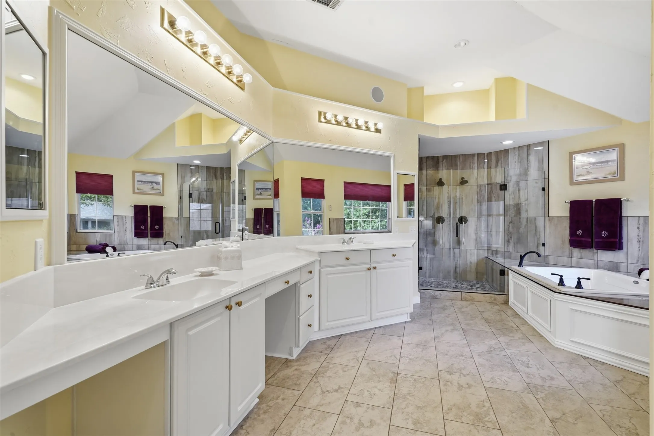 Spacious bathroom featuring an expansive dual vanity with integrated sinks, a built-in soaking tub, and a glass-enclosed shower with tiled walls