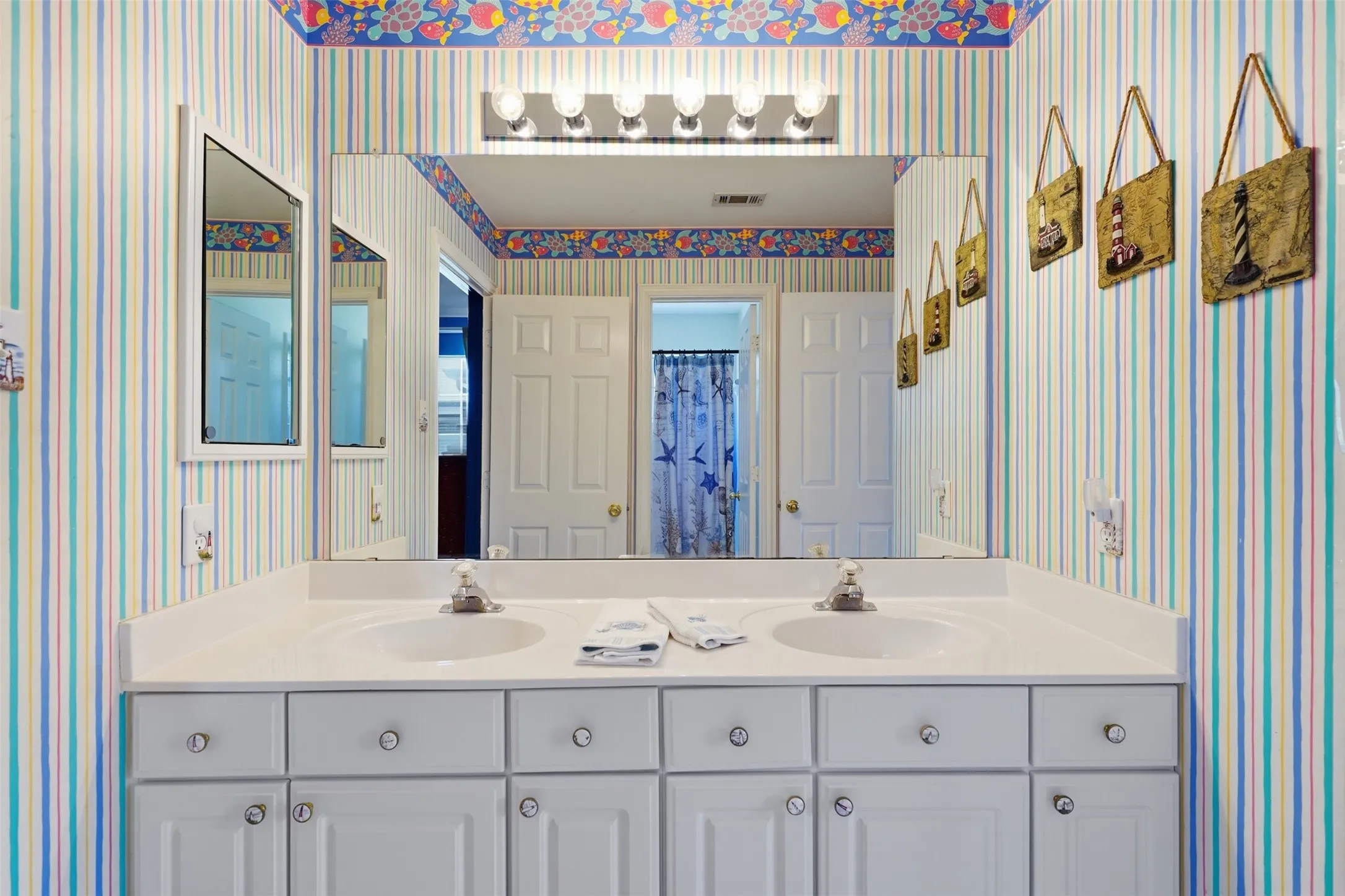 Double vanity with integrated sinks, white cabinetry, and wall-mounted light fixture
