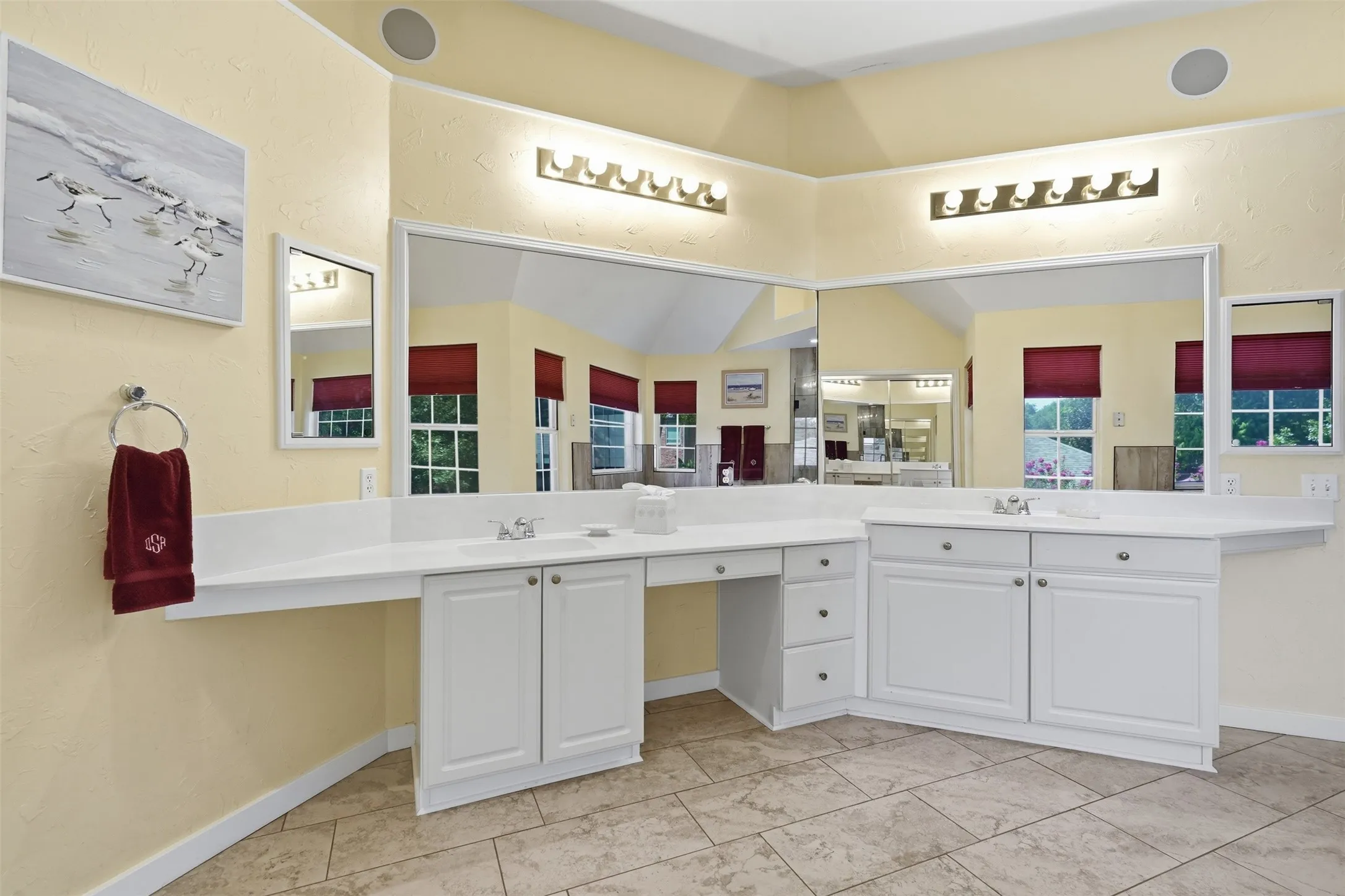 Dual vanity with white cabinetry, integrated sinks, white countertops, and expansive wall-mounted mirrors