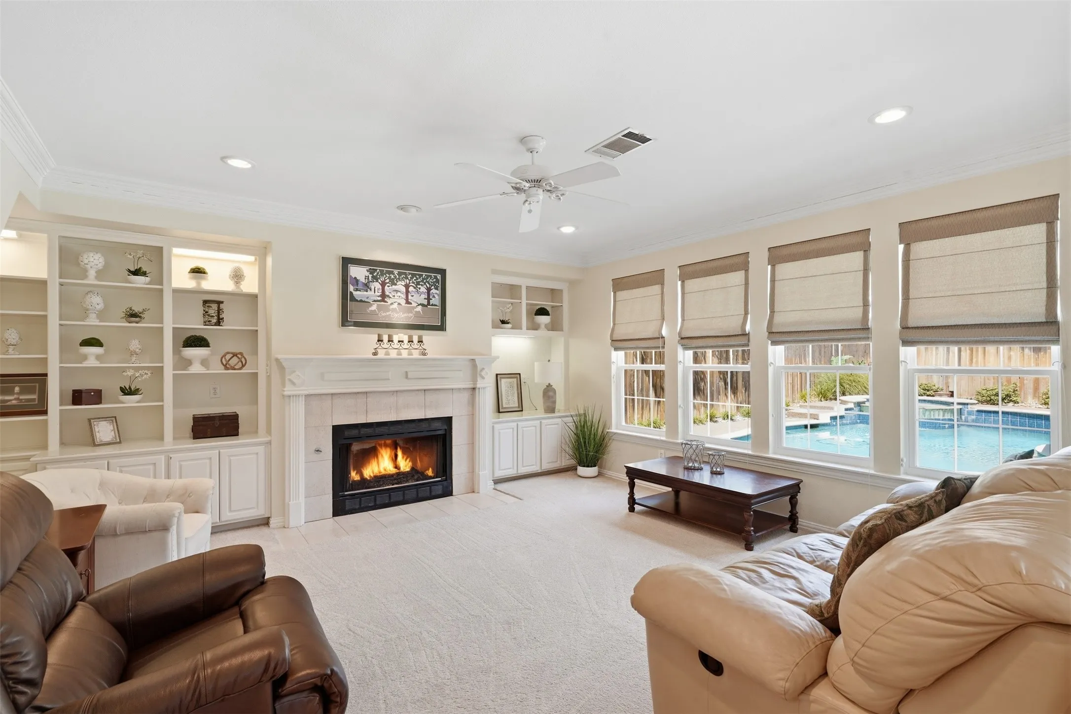 Living area featuring a fireplace with a tile surround, built-in shelving with integrated lighting, recessed lighting, and a ceiling fan