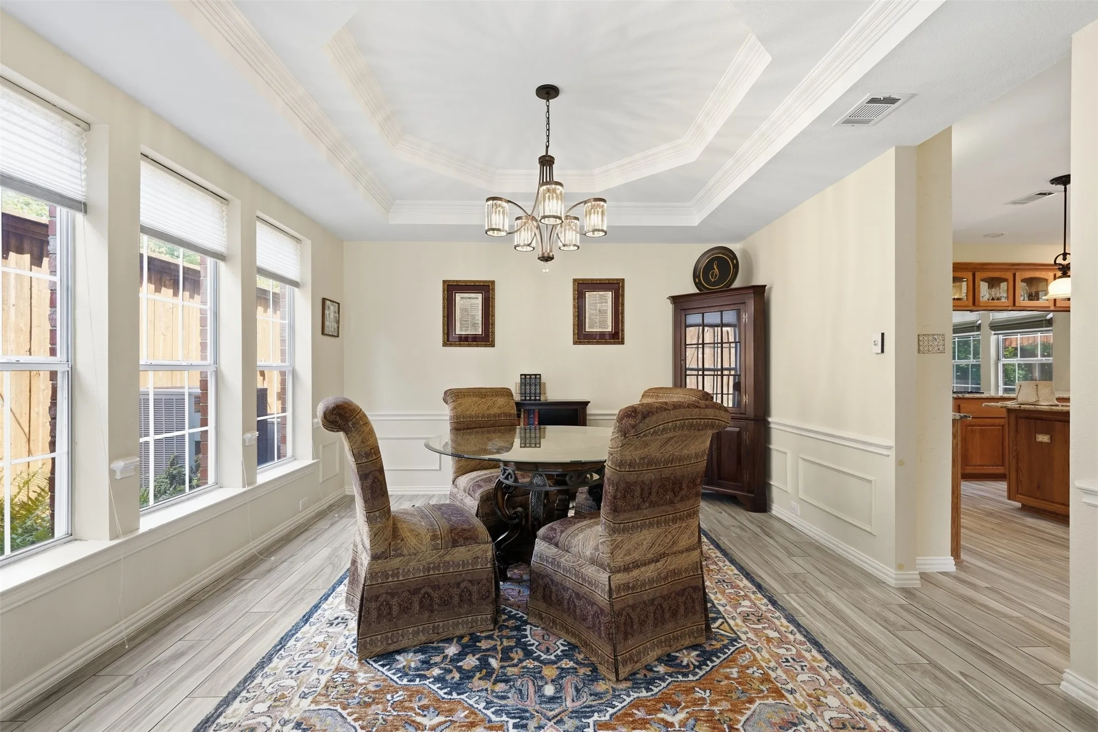 Dining area featuring a decorative tray ceiling with crown molding, chandelier lighting, and a chair rail with wainscoting