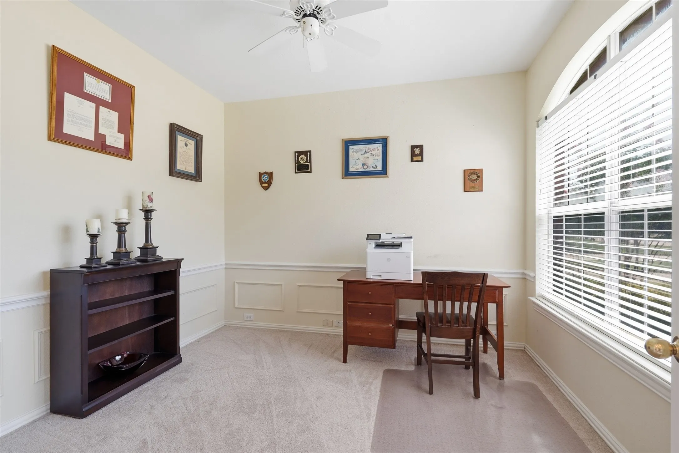 Room featuring neutral wall tones, chair rail molding, and an arched window with blinds