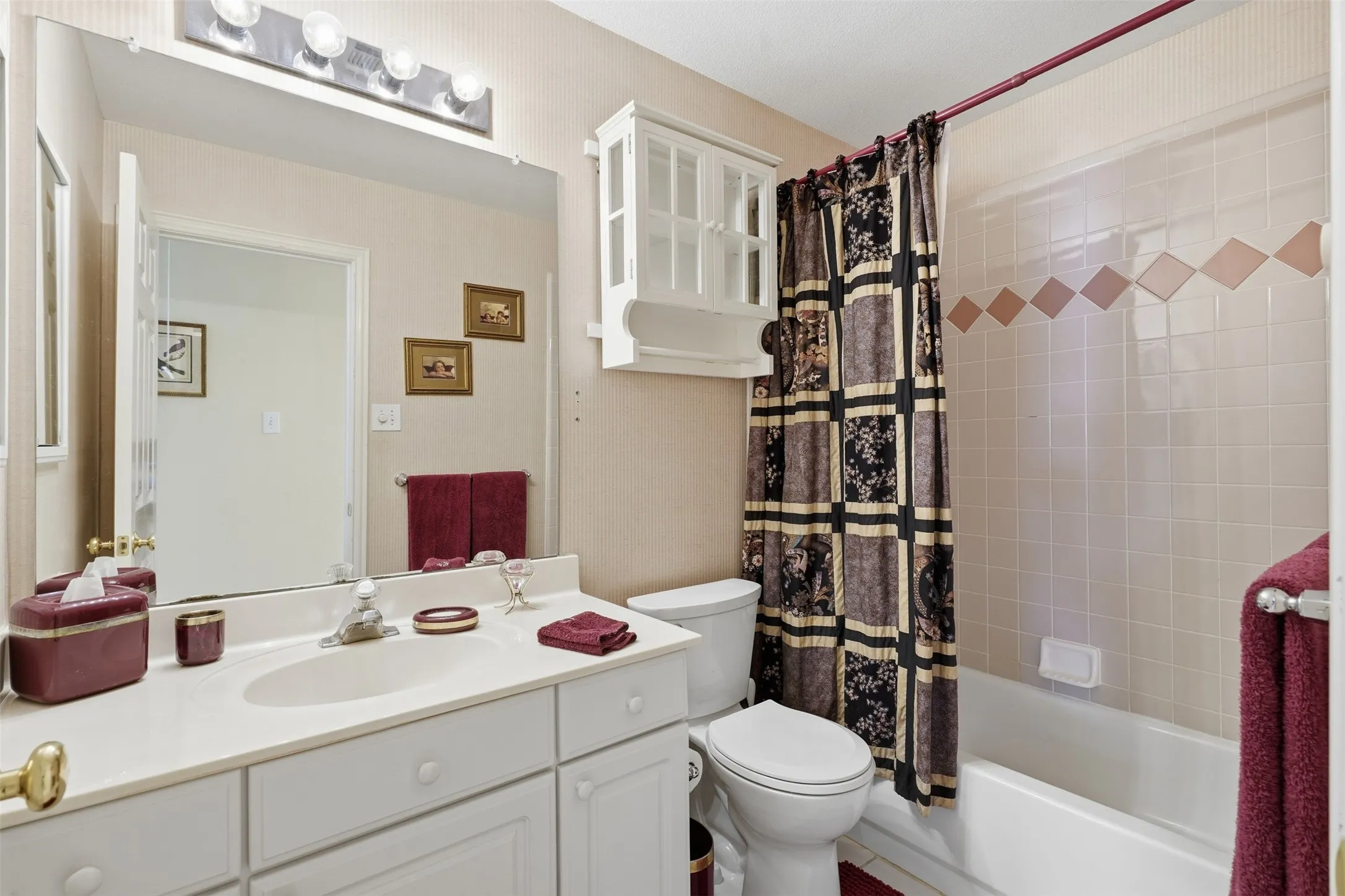 Bathroom featuring a white vanity with an integrated sink, a large wall-mounted mirror, and a four-light fixture