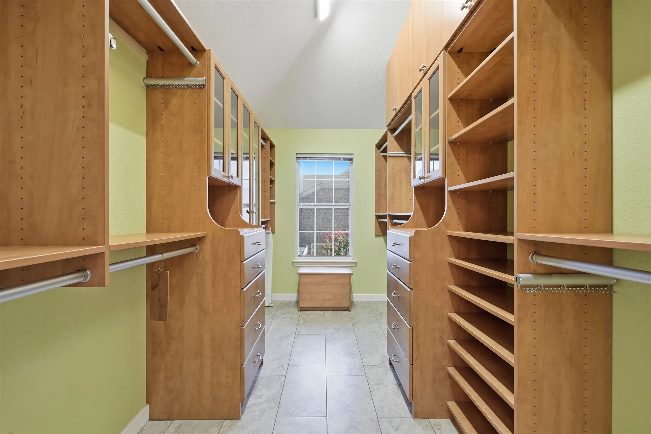 Custom wood-finish closet system featuring extensive shelving, hanging rods, built-in drawers with brushed nickel pulls, and upper cabinetry with glass inserts